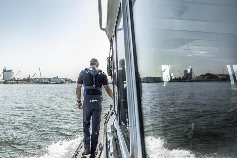 Douane duiker staat aan de zijkant van een boot